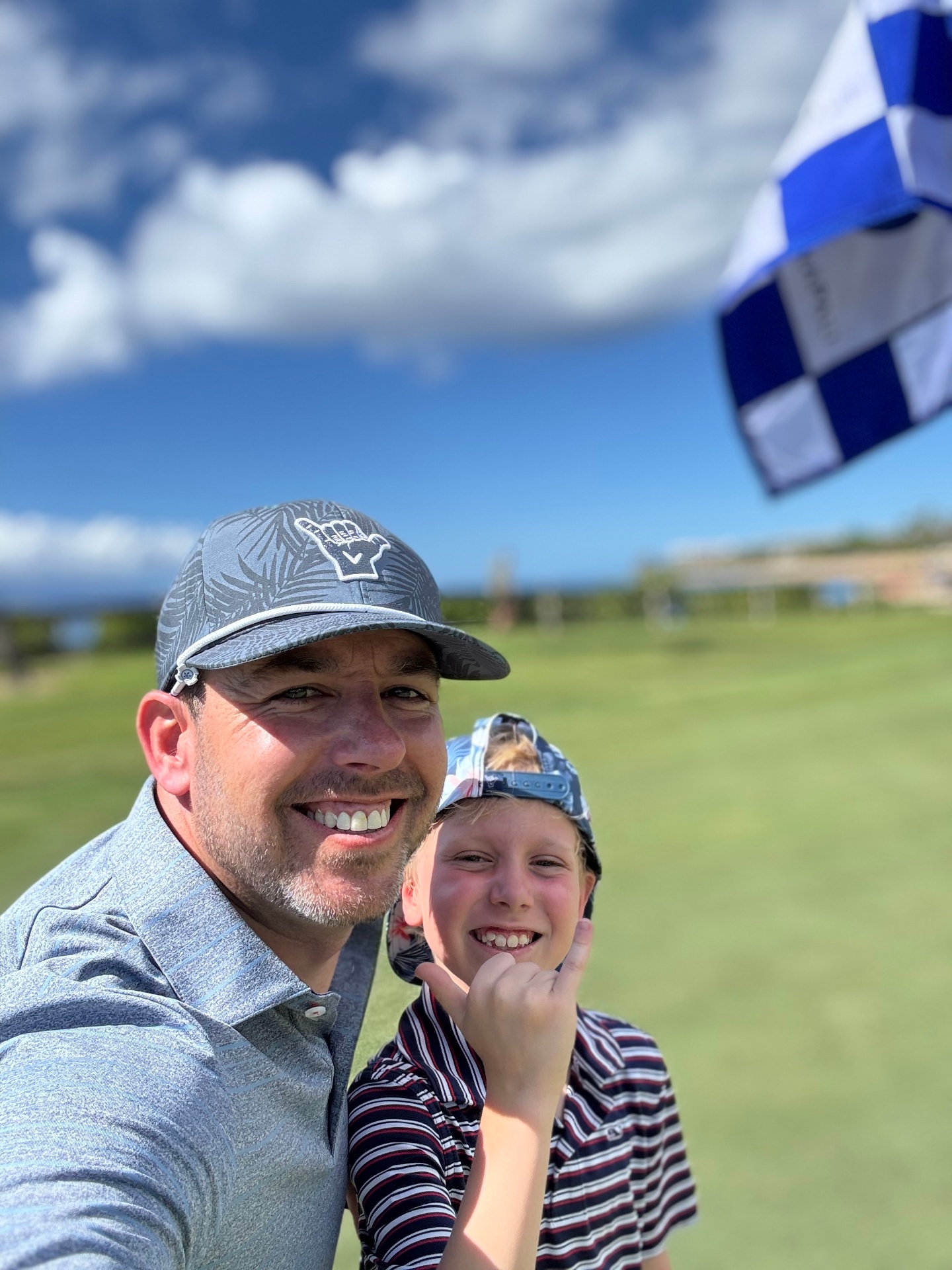 Nick and Hunter throwing shaka signs on a beachside golf course at golden hour